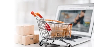 Carrito de compras con cajas frente a una laptop